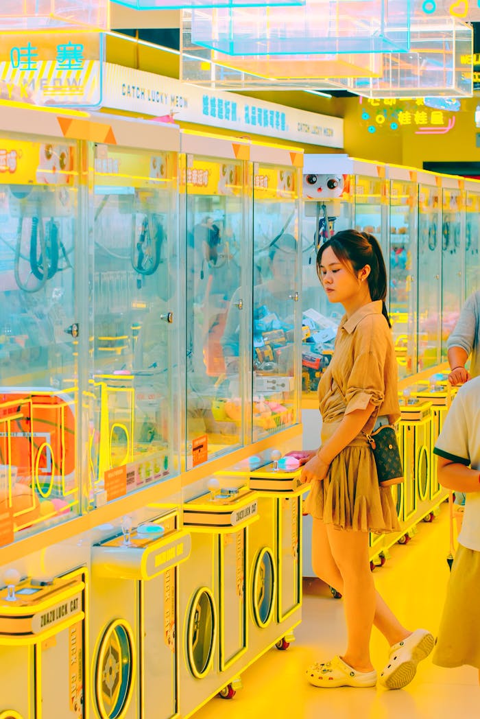 A young woman enjoys colorful claw machine games in a vibrant arcade.